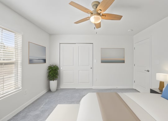 a white bedroom with a white bed and a ceiling fan