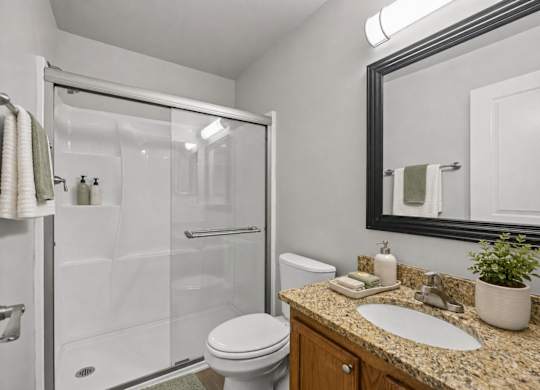 A bathroom with a toilet, sink, and shower.