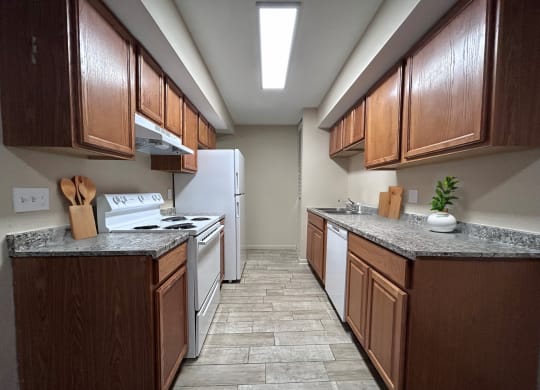 a kitchen with wood cabinets and white appliances and tile flooring