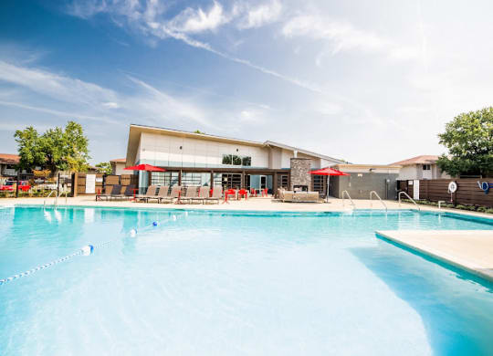 a large swimming pool with umbrellas and a building in the background at 7 Pointe Apartments, Indiana