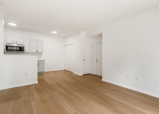an empty living room and kitchen with white walls and wood floors