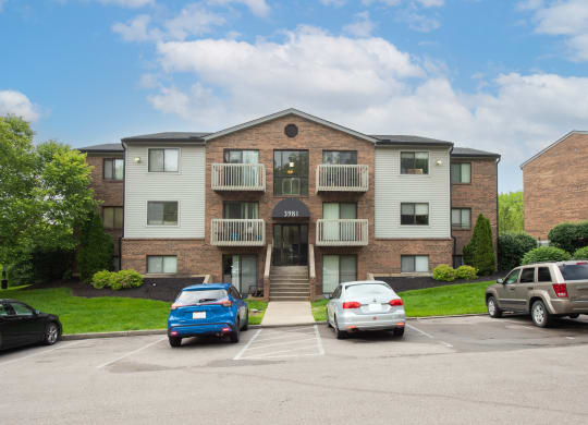 an apartment building with a parking lot and cars parked in front at The Woodridge Collection, Fairfield