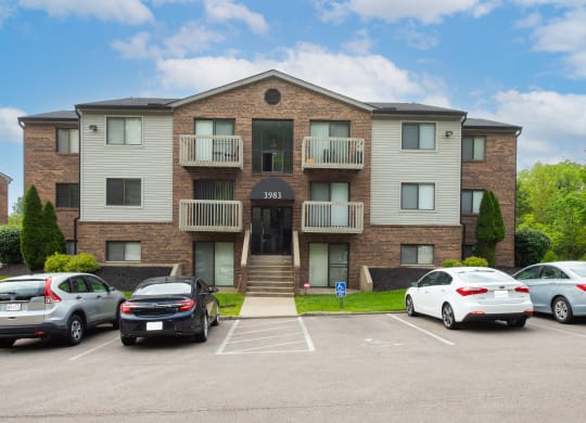 an apartment building with cars parked in front of it at The Woodridge Collection, Fairfield, OH 