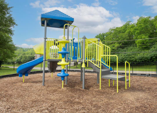 a playground with a blue and yellow swing set at The Woodridge Collection, Fairfield, OH 