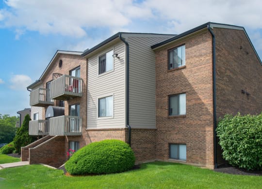 a brick apartment building with two balconies and a green yard at The Woodridge Collection, Fairfield, OH 