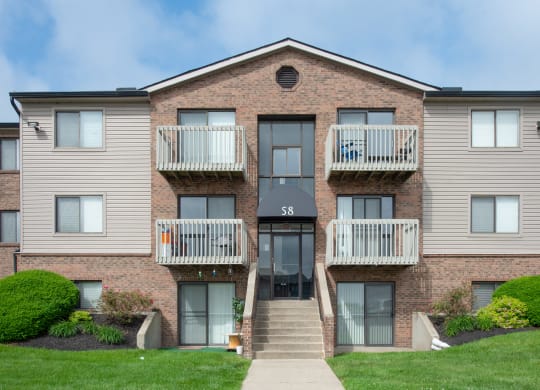 a brick apartment building with two balconies and a sidewalk at The Woodridge Collection, Fairfield