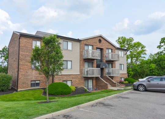 a brick apartment building with two balconies and a parking lot at The Woodridge Collection, Fairfield, OH 