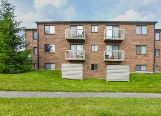 a brick apartment building with three balconies and a green lawn at The Woodridge Collection, Fairfield, Ohio