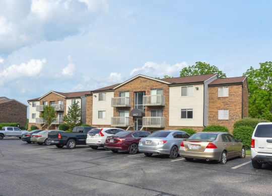 a parking lot with cars in front of an apartment building at The Woodridge Collection, Ohio