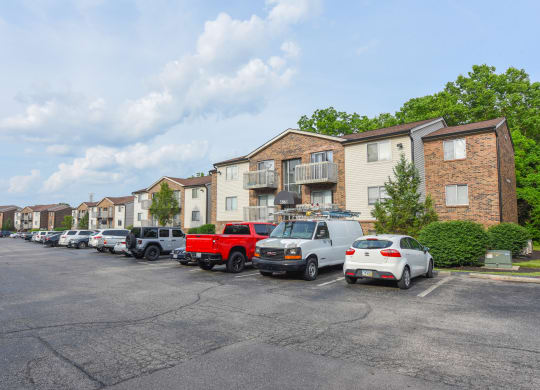 a parking lot filled with cars in front of apartment buildings at The Woodridge Collection, Fairfield