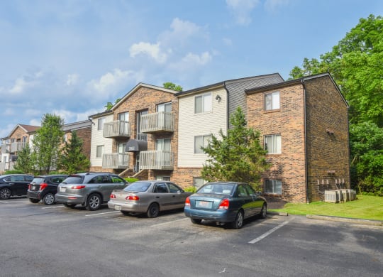 a parking lot with cars in front of an apartment building at The Woodridge Collection, Fairfield, OH 
