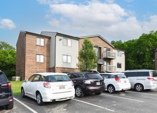 a group of cars parked in a parking lot in front of an apartment building at The Woodridge Collection, Fairfield, Ohio
