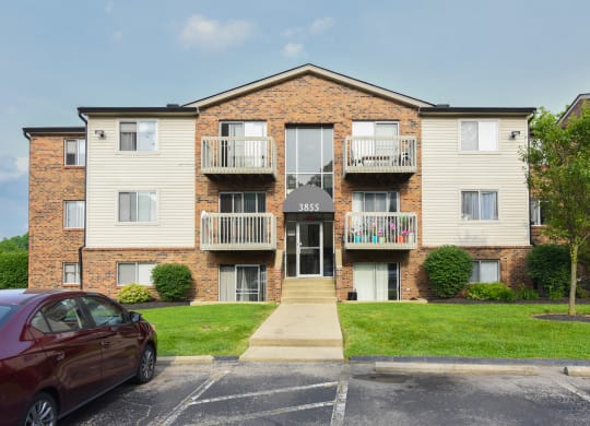 an apartment building with a red car parked in front of it at The Woodridge Collection, Fairfield, Ohio
