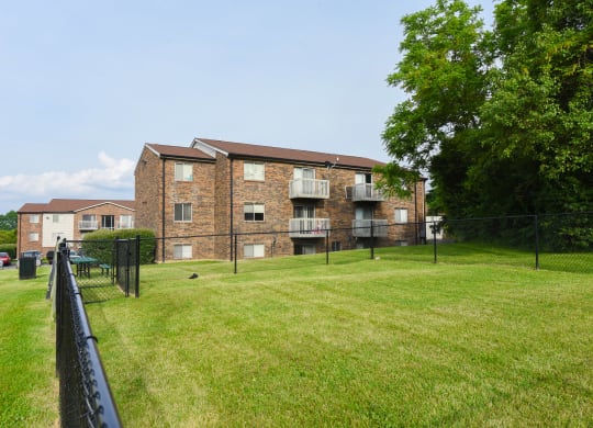 the back of an apartment building with a yard and a fence at The Woodridge Collection, Ohio, 45014