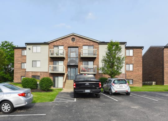 an apartment building with cars parked in a parking lot at The Woodridge Collection, Fairfield, Ohio