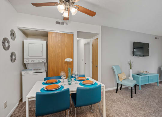 a dining area with a white table and blue chairs and a ceiling fan at The Woodridge Collection, Fairfield, OH 45014