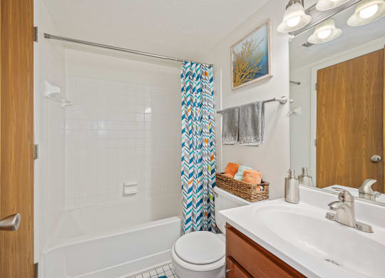 a bathroom with a white bathtub and a white sink with a blue and white shower curtain at The Woodridge Collection, Fairfield Ohio