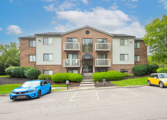 an apartment building with two cars parked in front of it at The Woodridge Collection, Fairfield, Ohio