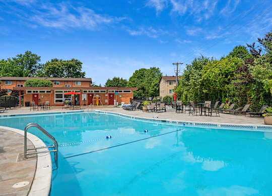 A large outdoor swimming pool surrounded by trees and lounge chairs at Rose Hill Apartments, Virginia