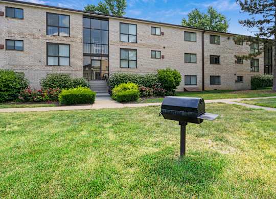 A black mailbox sits on a green lawn in front of a brick building at Rose Hill Apartments, Alexandria