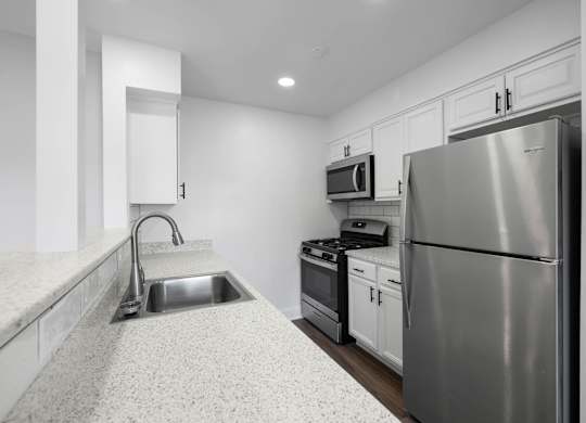 A modern kitchen with a stainless steel refrigerator, microwave, and oven at Rose Hill Apartments, Alexandria, VA, 22310