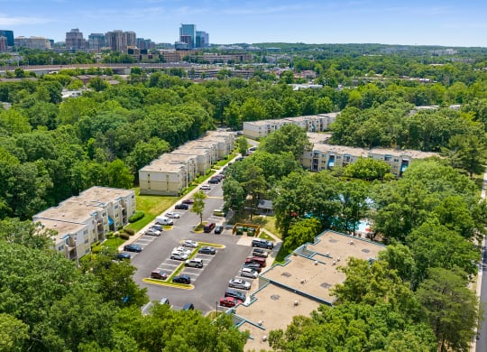 an aerial view of an apartment complex with trees and a city in the background