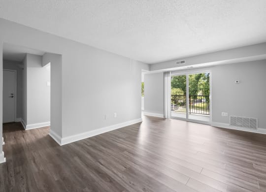 the living room of an empty apartment with wood flooring and a sliding glass door