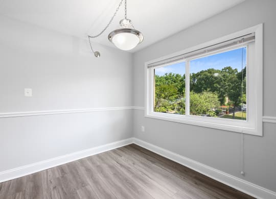 an empty bedroom with a large window and wood flooring
