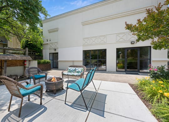 a patio with chairs and a fire pit and a building in the background