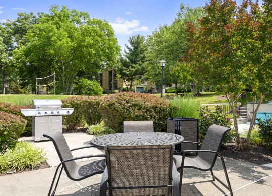 a patio with a table and chairs and a grill
