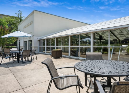 a patio with tables and chairs and a building in the background