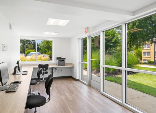 an office with windows and a desk with chairs and a computer