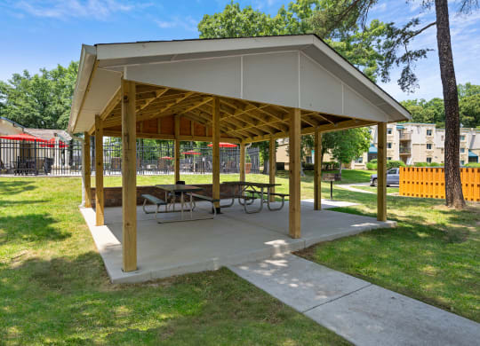 a picnic pavilion with benches and tables in a park