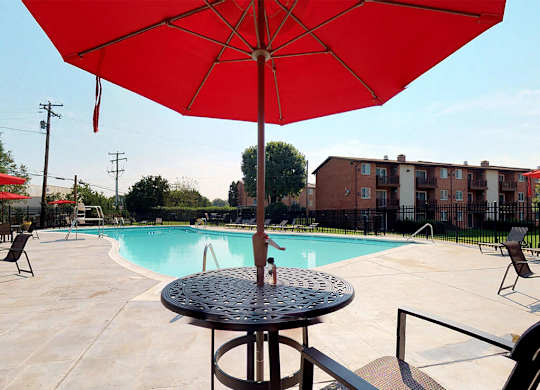 Large red umbrella with table near side of the pool at Rose Hill Apartments, Alexandria, VA, 22310