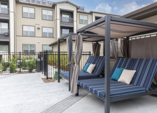 a patio with a canopy bed in front of an apartment building