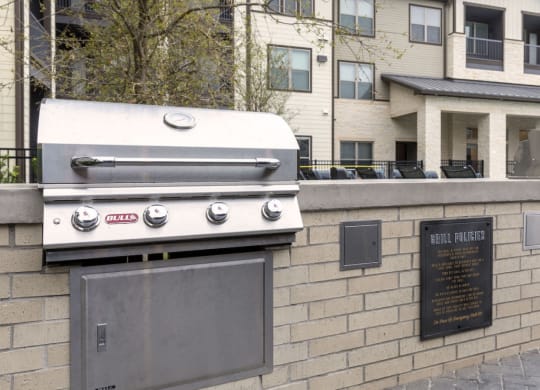a barbecue grill on a brick wall in front of an apartment building