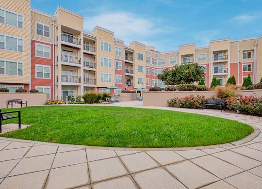 a courtyard with a green grassy area and an apartment building in the background
