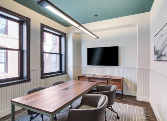 a conference room with a wooden table and chairs and a flat screen tv on the wall
