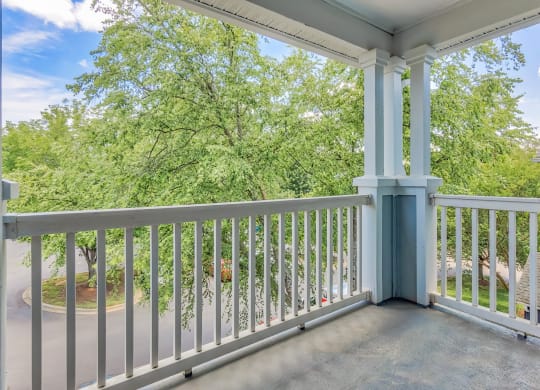 A balcony with a white railing and a tree in the background