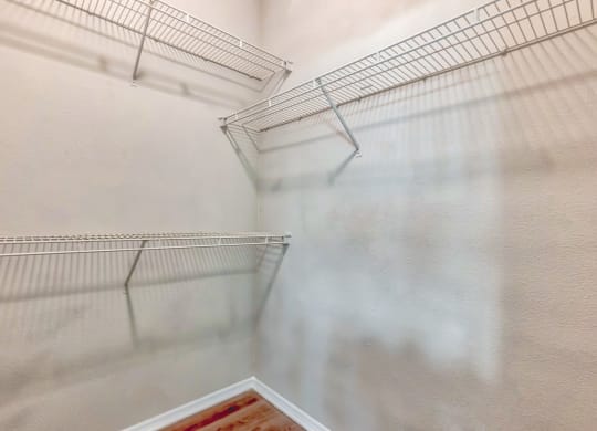 A walk in closet in a bedroom with white walls and metal shelves