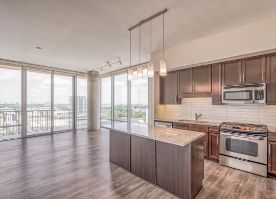 Kitchen and living room with wood flooring and large windows at The Sovereign at Regent Square, 3233 West Dallas, Houston, TX