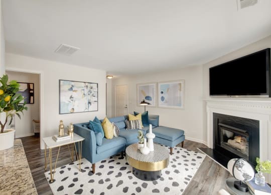Living room with blue couches and a large tv above a fireplace at Windsor Kingstowne, VA 22315