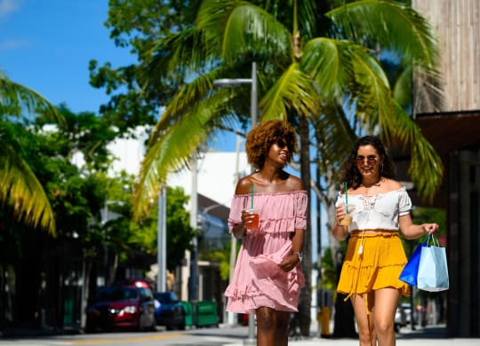 People walking down the street with drinks in their hands in the area nearby Windsor Biscayne shores in North Miami