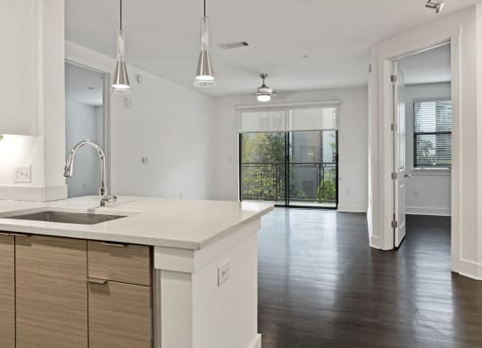 An empty kitchen with a sink and a door to a living room at The Encore by Windsor, Atlanta, 30339