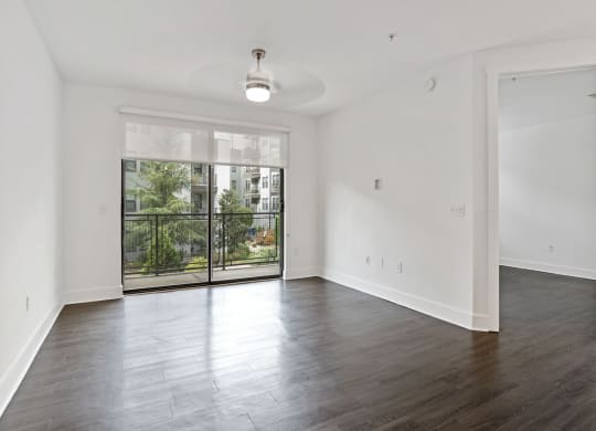 An empty living room with a large window and a balcony at The Encore by Windsor, Atlanta, 30339