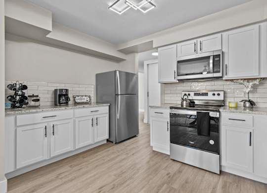 A modern kitchen with white cabinets and stainless steel appliances.
