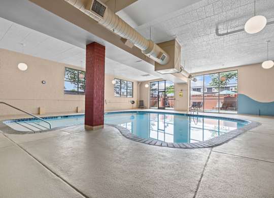A large indoor swimming pool with a red pillar and a metal ladder.