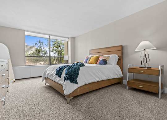 A bedroom with a large bed and a window overlooking a cityscape.