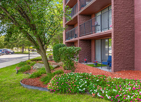 A red brick building with a balcony and a tree in front.