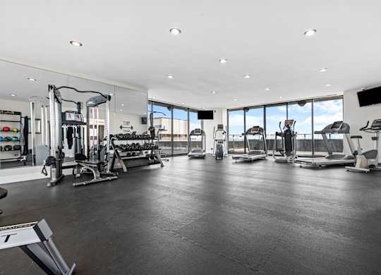 A spacious gym with a variety of equipment and a large window.